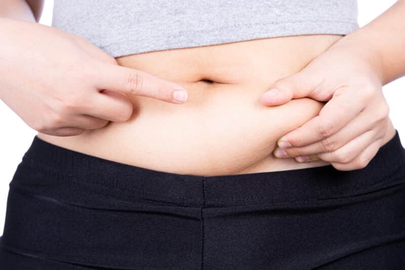 Woman pinching excessive fat on her belly.